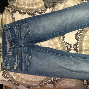 Blå jeans från Diesel - Säljer ett par snygga blå jeans från Diesel i storlek 26. De har en klassisk femficksdesign och är tillverkade i 100% bomull. Perfekta för vardagsbruk dom är lågmidjade och är en stilren look. Passar både till vardags och fest! Pris kan även diskuteras om det skulle vara nått.