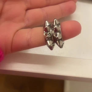Silvriga örhängen med nitar - Snygga och trendiga silvriga örhängen med coola nitar. Perfekta för att ge din outfit en edgy touch. De är små och lätta, vilket gör dem bekväma att bära hela dagen. Passar både till vardags och fest!Från Edblad och kostar igentligen 399