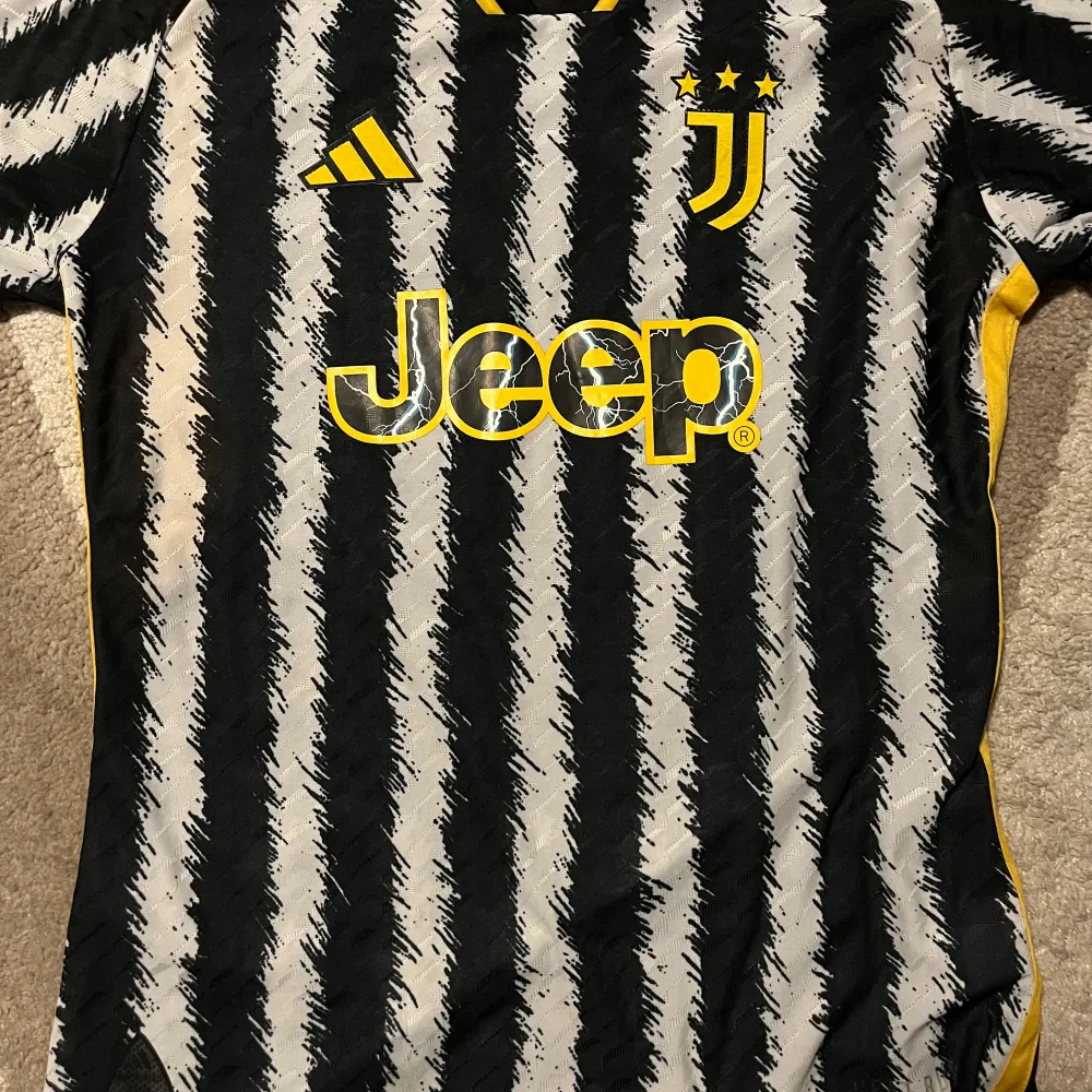 Säljer en Juventus fotbollströja i svart och vit med gula detaljer. Tröjan har korta ärmar och ett coolt randigt mönster. Strl l men passar m och s beror på kroppsstorlek . T-shirts.