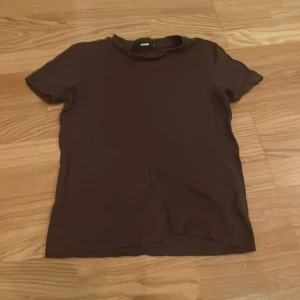 Brun t-shirt från BikBok - Säljer en enkel och stilren brun t-shirt från BikBok i storlek XS. Perfekt basplagg för vardagsbruk. T-shirten har korta ärmar och en rund halsringning. Passar bra till både jeans och kjol. 🧡