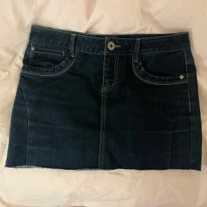 Mörkblå jeanskjol - Mörkblå jeanskjol med coola sömmar på fickorna! 🤍Köpt secondhand och det står ingen storlek men den är lite lös på mig som vanligtvis har S