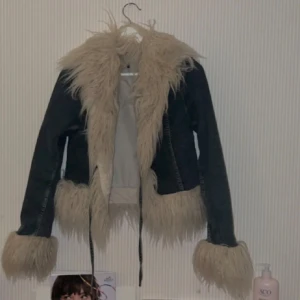 Jeansjacka med pälsdetaljer - Säljer en snygg jeansjacka med fluffiga pälsdetaljer i beige. Jackan har långa ärmar och en cool stil med päls vid krage, ärmslut och nederkant. Perfekt för höst och vår när du vill sticka ut lite extra. Passar bra till både vardag och fest!