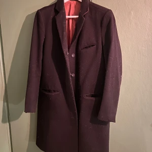 Svart kappa från Filippa K - Säljer en elegant svart kappa. Den har en klassisk design med knappar framtill och långa ärmar. Tyvärr är fodret trasigt, men utsidan är i bra skick. Perfekt för höst och vinter! Den är väldigt varm. Som man ser på bilderna är sidenet på insidan trasigt, men det syns inte från framsidan. En av knapparna har trillat av, men det är inget som syns. Väldigt varm och skön!