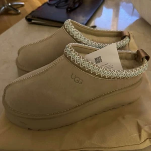 Beige UGG skor - Säljer ett par snygga beige UGG skor i mocka. Perfekta för höst och vinter, och de ser supermysiga ut! Skorna är i nytt skick och kommer med originalpåse. 