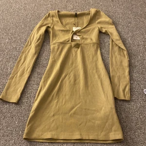 Olivgrön ribbad klänning  - Säljer en superfin olivgrön ribbad klänning i storlek S. Klänningen har en v-ringad design och långa ärmar, perfekt för höst och vår. Den är i nytt skick med prislappen kvar. Passar både till vardags och fest!