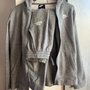 Nike mjukisset  - Fint, grått mjukisset från Nike 🩶 fodrad insida på både över-och underdelen vilket håller en varm under kalla vintrar! Den är i barnstorlek 158-170 men passar mig som brukar ha XS och är 160 lite oversized. 