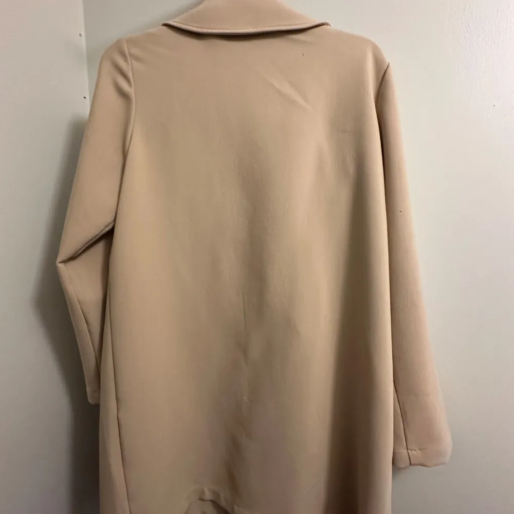 En stilren beige kappa från Flash Woman i storlek M!  Den har en klassisk design med dubbelknäppning med jättefina knappar och stora slag. Perfekt för höst och vår och är oanvänd! . Jackor.