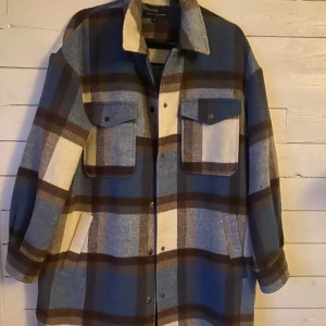 Kappa från Kappahl, stl. M - NY! - Säljer en superfin rutig Kappa från KappAhl . Den har en skön oversized passform. Färgerna är en mix av blått, brunt och beige. Helt NY! 