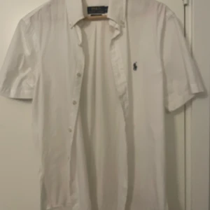 Ralph Lauren skjorta - Säljer en vit kortärmad Ralph Lauren skjorta. Den är köpt i somras och använd Max 3 gånger. Inget fel på det jag säljer den bara för den är lite för stor. Hör av er om ni har nån fråga💯👍