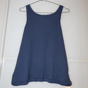 Blå linnetopp från 157 - Säljer en enkel och stilren blå linnetopp från 157 i storlek XL. Toppen är ärmlös och tillverkad i 100% bomull, vilket gör den perfekt för varma sommardagar. Den har en rund halsringning och en avslappnad passform. Perfekt för en casual look eller som basplagg i garderoben.
