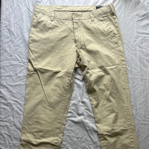 Beige chinos från Polo Ralph Lauren - Säljer ett par snygga beige chinos från Polo Ralph Lauren i slim fit. De är i bra skick och perfekta för både vardag och fest. Byxorna har en klassisk design med knappar och fickor bak. Passar perfekt till en stilren look!