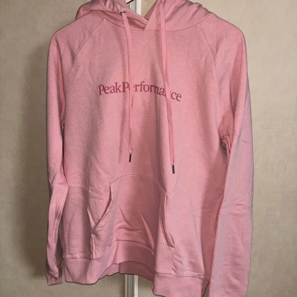 Säljer en superfin rosa hoodie från Peak Performance i storlek XL. Den är i bra skick och perfekt för både höst och vår. Hoodien har en klassisk design med känguruficka och justerbar huva. Perfekt för en avslappnad stil! 💖. Hoodies.