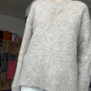 Beige stickad tröja - Mysig beige stickad tröja med v-ringning i materialet alpacka ull. Tröjan har långa ärmar och en loose passform som gör den superbekväm att bära. Passar till allt! Perfekt nu till hösten💕 helt oanvänd.