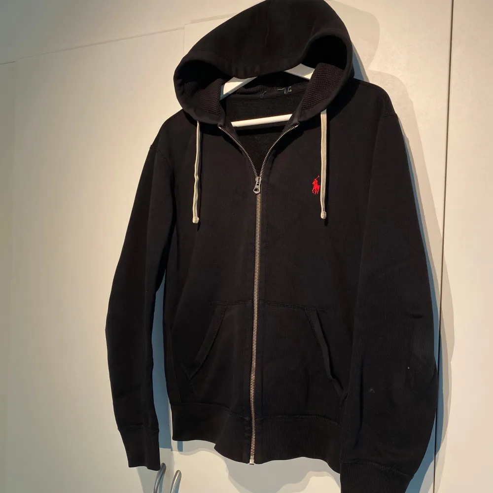 Polo Ralph Lauren Zip-Hoodie i svart med röd häst. Fint skick utan skador. Storlek M. Unisex. Nypris 1900kr. Stilsäker som går att både dressa upp & ner. Grymt bra basplagg i garderoben. Funkar året runt. Pris kan diskuteras. Hör av dig i DM! . Hoodies.