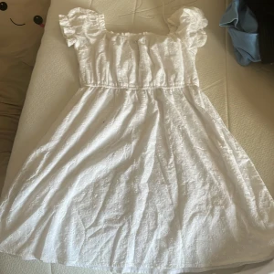 Vit klänning från Sister - Säljer en superfin vit klänning från New yorker i storlek M. Den har ett sött broderat mönster och korta puffärmar. Perfekt för sommarens alla fester eller en mysig dag på stan. Klänningen har en elastisk midja för en bekväm passform. 🌸