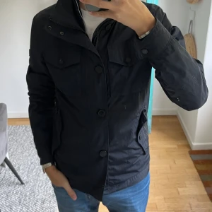 J. Lindeberg Bailey Fieldjacket - Mörkblå fieldjacket från J.Lindeberg i modellen Bailey.  Fint skick förutom att knappen längst ner har lossnat, men inget som man tänker på. Storlek S