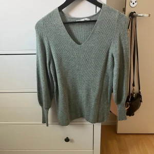 Grå ribbad tröja från ONLY - Säljer en stilren och bekväm grön ribbad tröja från ONLY. Den har en snygg v-ringning och långa ärmar, perfekt för både vardag och lite finare tillfällen. Tröjan är i bra skick och passar perfekt till höst- och vintergarderoben.