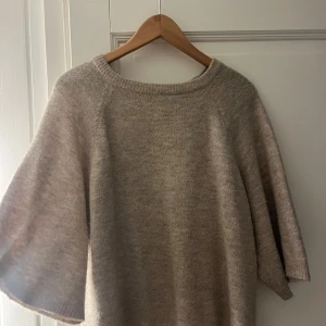 Beige stickad tröja från 157 - Säljer en supermysig beige stickad tröja från märket 157. Den har en enkel och stilren design med rund hals och trekvartsärmar. Perfekt för höst och vinter när du vill hålla dig varm och snygg. Tröjan är i storlek M och passar perfekt för en avslappnad look.