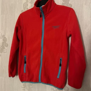 Röd fleecejacka från Swedemount - Säljer en hallonröd fleecejacka från Swedemount med blå dragkedjor. Inte mycket använd, riktigt fin! Passar lika bra till tjej som kille