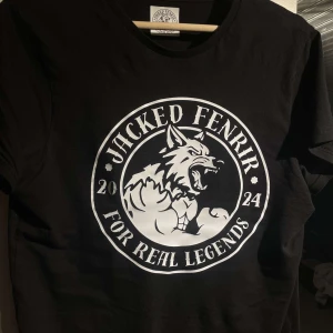 Svart t-shirt med tryck från Jacked Fenrir UF - Finns i alla storlekar. Snygg svart t-shirt från Jacked Fenrir med ett stort tryck av en muskulös varg och texten 'For Real Legends'. Perfekt för dig som vill sticka ut med en cool design. T-shirten har korta ärmar och en rund halsringning. 