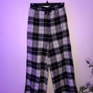 Pjamasbyxor svarta/vita - Snygga och bekväma pjamas byxor i svartvitrutigt mönster. De har en loose passform och är tunna. Byxorna har snörning i midjan för justerbar passform.