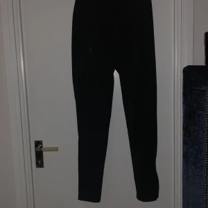 Svarta träningsbyxor från Under Armour - Säljer ett par svarta träningsbyxor från Under Armour. Byxorna har en elastisk midja och är tillverkade i ett syntetmaterial som ger bra rörlighet. Perfekta för träning och andra sportaktiviteter. Byxorna är i nyskick använt fåtal gånger 