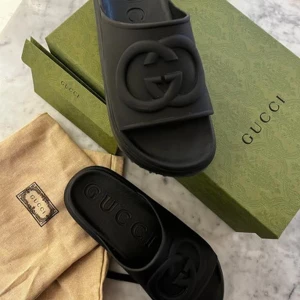 Svarta sandaler från Gucci - Snygga svarta sandaler från Gucci med det ikoniska GG-logotypen på ovansidan. Sandalerna har en robust sula med mönster för extra grepp. Perfekta för en stilren look.