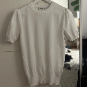 Vit tröja från Saint Tropez - Säljer en stilren vit tröja från Saint Tropez. Tröjan har korta ärmar med en lätt puff och en rund halsringning. Perfekt för en enkel och elegant look. Passar bra till både jeans och kjol