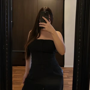 Jumpsuit - Snygg svart axelbandslös jumpsuit från H&M med en tight passform. Perfekt för en stilren look. Jumpsuiten har en dragkedja på sidan för enkel påklädning. Passar utmärkt till både klackar och sneakers.🥰🥰🥰
