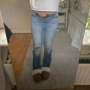 Blå bootcut jeans low waisted  - Säljer ett par snygga blå bootcut jeans med slitningar på knäna. Midjemått: stretchas upp till 26, innerbensmått 83 (lånade bilder från förra ägaren)