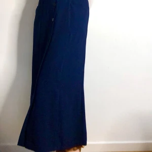 Mörkblå långkjol med knappar - Elegant mörkblå långkjol med knappar framtill. Kjolen har en klassisk design och en rak passform som ger en stilren look. Perfekt för en chic och tidlös stil. Jag skulle bedöma den som lite liten i storleken. Jag har ofta 38 och är 173 cm lång, och den sitter bra på mig. (Finns på fler säljsidor)