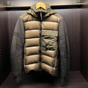 Grön jacka från C.P. Company - Säljer en snygg grön jacka från C.P. Company. Jackan har en quiltad framsida med dragkedja och en huva. Ärmarna och baksidan är stickade, vilket ger en cool kontrast. Perfekt för kyligare dagar!