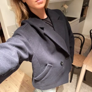 Matinblå jacka - Snygg blå kort kapp med knappar framtill och klassisk krage. Perfekt för en stilren look. Passar bra till det mesta!