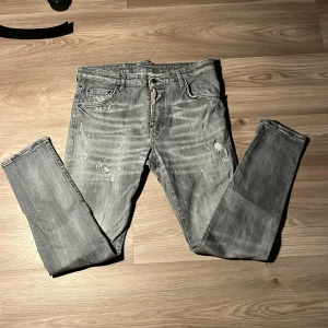 Grå jeans från Dsquared2 - Snygga grå jeans från Dsquared2 med slitna detaljer och en cool tvättad look. De har en klassisk femficksdesign och knappgylf. Perfekta för en avslappnad stil med en touch av edge.