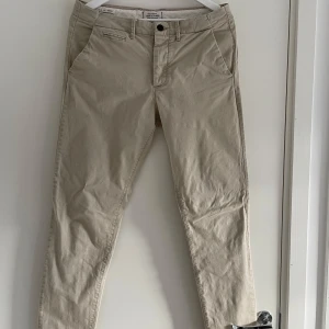 Beige chinos från Jack & Jones - Snygga beige chinos från Jack & Jones med normal passform. Finns en liten fläck på byxan