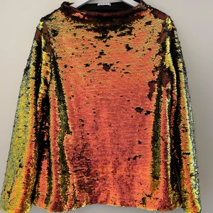 Wera ny topp med paljetter - •Snygg och iögonfallande Wera-topp med lång ärm och hög krage.  •Aldrig använd, bara tvättad •Storlek: 42 •Toppen är täckt med skimrande paljetter i en gradient av färger, från mörkare toner till ljusare. •Paljetterna ger en festlig och elegant look.  •Toppen har en bekväm passform och är perfekt för festliga tillfällen eller andra speciella evenemang. •Djurfritt och rökfritt hem