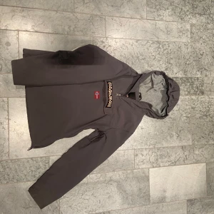 Grå jacka från Napapijri - Säljer en grå jacka från Napapijri med huva och norsk flagga på framsidan. Jackan har en dragkedja framtill och en stor ficka med dragkedja. Perfekt för kyligare dagar med sin stilrena design och praktiska detaljer. För nån som är 160-170 cm lång 