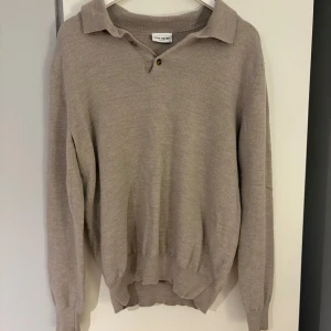 Beige tröja från John Henric - Säljer en stilren beige tröja från John Henric. Tröjan har en klassisk krage med knappar och långa ärmar. Tröjan har krympts i tvätten. Detta märks tydligt på material och passform. Men tröjan ser fortfarande bra ut och kan klart användas. Tröjan är M original men sitter numera mer som en XS