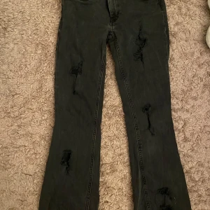 Svarta jeans med slitningar - Snygga svarta jeans med slitningar på framsidan. De har en klassisk femficksdesign och en bekväm passform. Perfekta för en avslappnad stil. Dom är lågmidjade, korta på mig som är 170cm. Avklippta längst ner vid fötterna