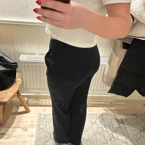 Mörkblåa kostymbyxor - Snygga mörkblåa kostymbyxor med medelhög midja och rak passform. Perfekta för en stilren look. Byxorna har en klassisk design med knäppning fram.