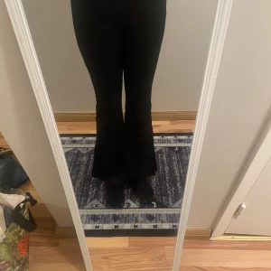 Svarta byxor med slits - Snygga svarta byxor med bootcut-stil och slits vid anklarna. Perfekta för en trendig look. De är högmidjade och har en tight passform som framhäver figuren.