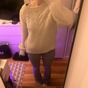 Beige stickad tröja med flätmönster - Mysig beige stickad tröja med ett snyggt flätmönster på framsidan. Tröjan har långa ärmar och en rund halsringning, perfekt för kyliga dagar. Den är både stilren och bekväm, vilket gör den till ett måste i garderoben. Inga defekter! Men väl använd och har lite glitter detaljer som tyvärr inte syns på kamera!❤️