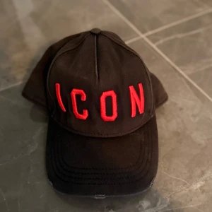  Dsquared2 ”ICON” keps - Snygg svart keps från Dsquared2 med röd broderad text 'ICON' på framsidan. Perfekt för en cool och avslappnad stil. Inköpt på Room 1006 i Malmö.