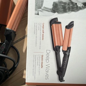 Locktång för stora vågor från BaByliss - Deep waves. Säljer en locktång från BaByliss som skapar stora, mjuka vågor. Den har en kopparfärgad design och är enkel att använda för snabba resultat. Perfekt för att få till de där djupa vågorna i håret.