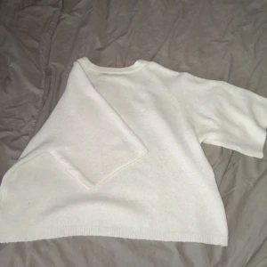 Vit stickad tröja - Säljer en mysig vit stickad tröja med trekvartsärmad design. Perfekt för kyligare dagar och enkel att matcha med olika outfits. Tröjan har en klassisk passform och är gjord i ett mjukt material.