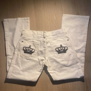 Vita jeans med kronbroderi🤍😍✨ - Snygga vita jeans med unikt svart kronbroderi på bakfickorna med lite glitter från Victoria Beckham.           Jag säljer dessa för dem var för små för mig (1,67cm) Priset kan diskuteras!🤍
