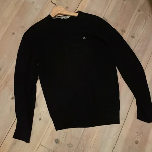 Svart merinoull tröja från J.Lindeberg - Säljer en stilren svart tröja från J.Lindeberg. Tröjan har långa ärmar och en liten logga på bröstet. Perfekt för en minimalistisk look. Sitter i storlek M men sitter för litet för mig som är 185 cm, kan passa S 