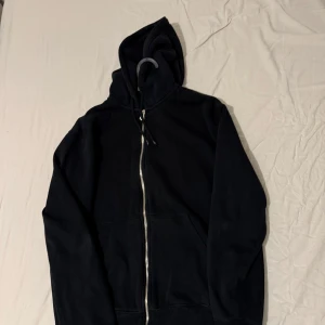 Svart hoodie från weekday med luva - Säljer en klassisk svart hoodie med dragkedja ifrån weekday och huva. Perfekt för en avslappnad stil. Den har långa ärmar och en praktisk ficka framtill. Pris kan diskuteras.