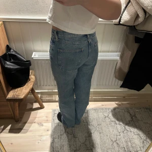 Blå jeans med medelhög midja - Snygga blå jeans med hög midja och klassisk femficksdesign. De har en straight passform som ger en tidlös look. Perfekta för en avslappnad stil.