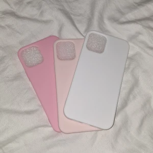 Tre mobilskal i olika färger - Säljer tre snygga mobilskal i olika färger: rosa, ljusrosa och vit. Perfekta för att skydda din telefon samtidigt som de ser trendiga ut. Passar till iPhone-modell 12💕